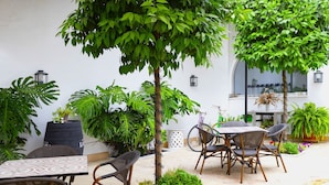 An outdoor patio area with tables and chairs, surrounded by various potted plants and a small tree. - Albariza Hotel Boutique (Sanlucar de Barrameda)