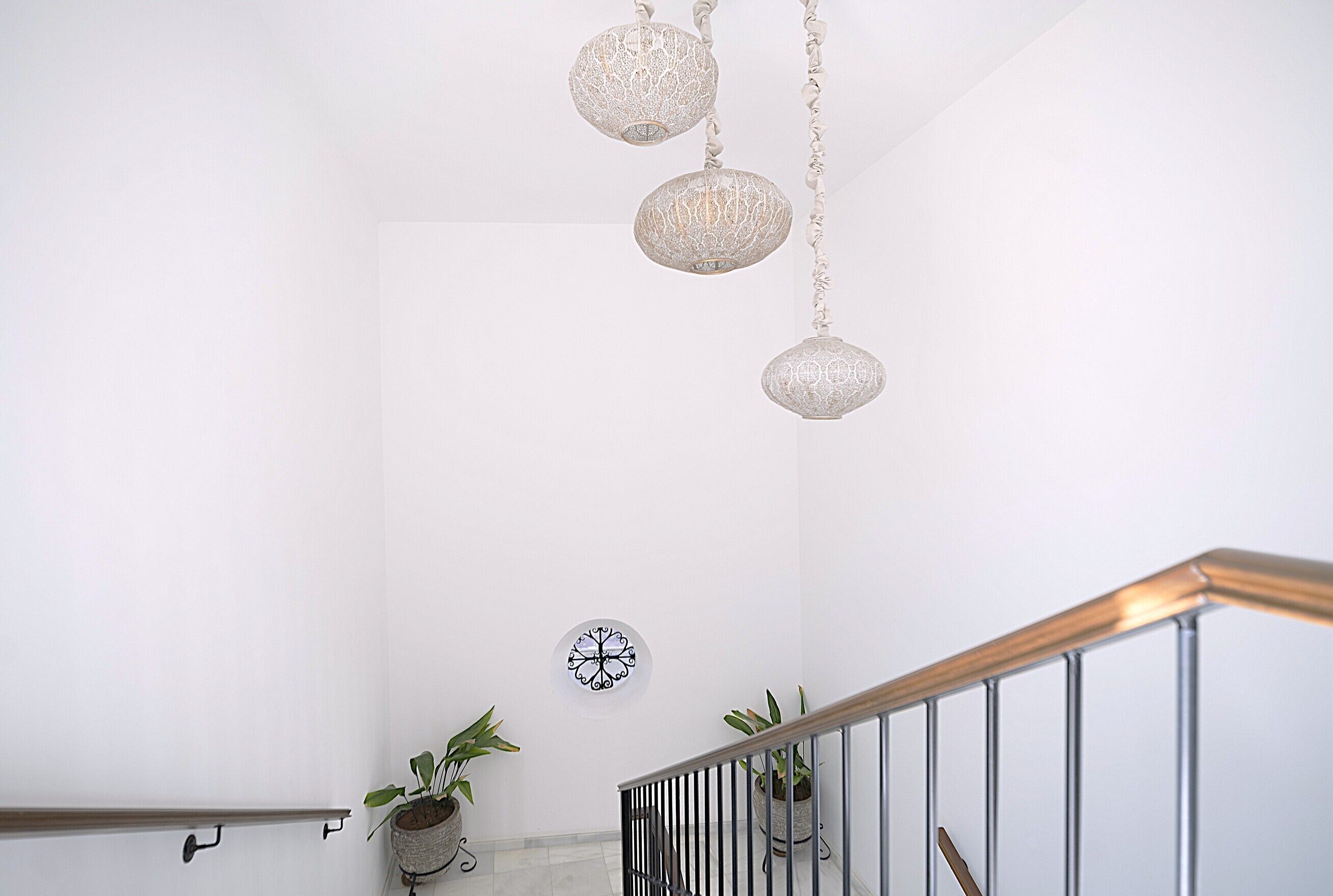 A staircase with a metal railing, a wall-mounted clock, and hanging decorative lights.