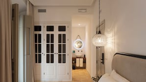 A bedroom with a bed, a bedside table, a hanging light fixture, and a bathroom visible through an open door. - Albariza Hotel Boutique (Sanlucar de Barrameda)