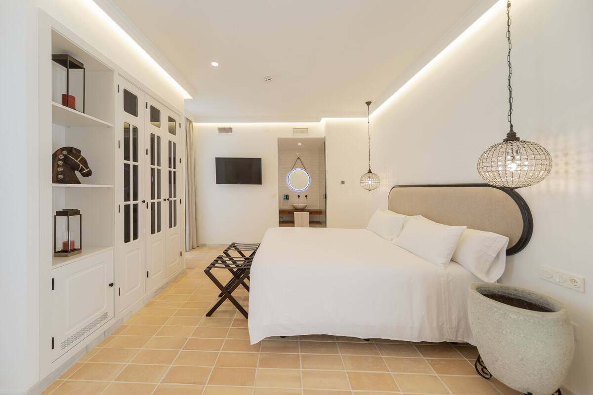 A bedroom with a bed, wardrobe, and a TV on the wall.