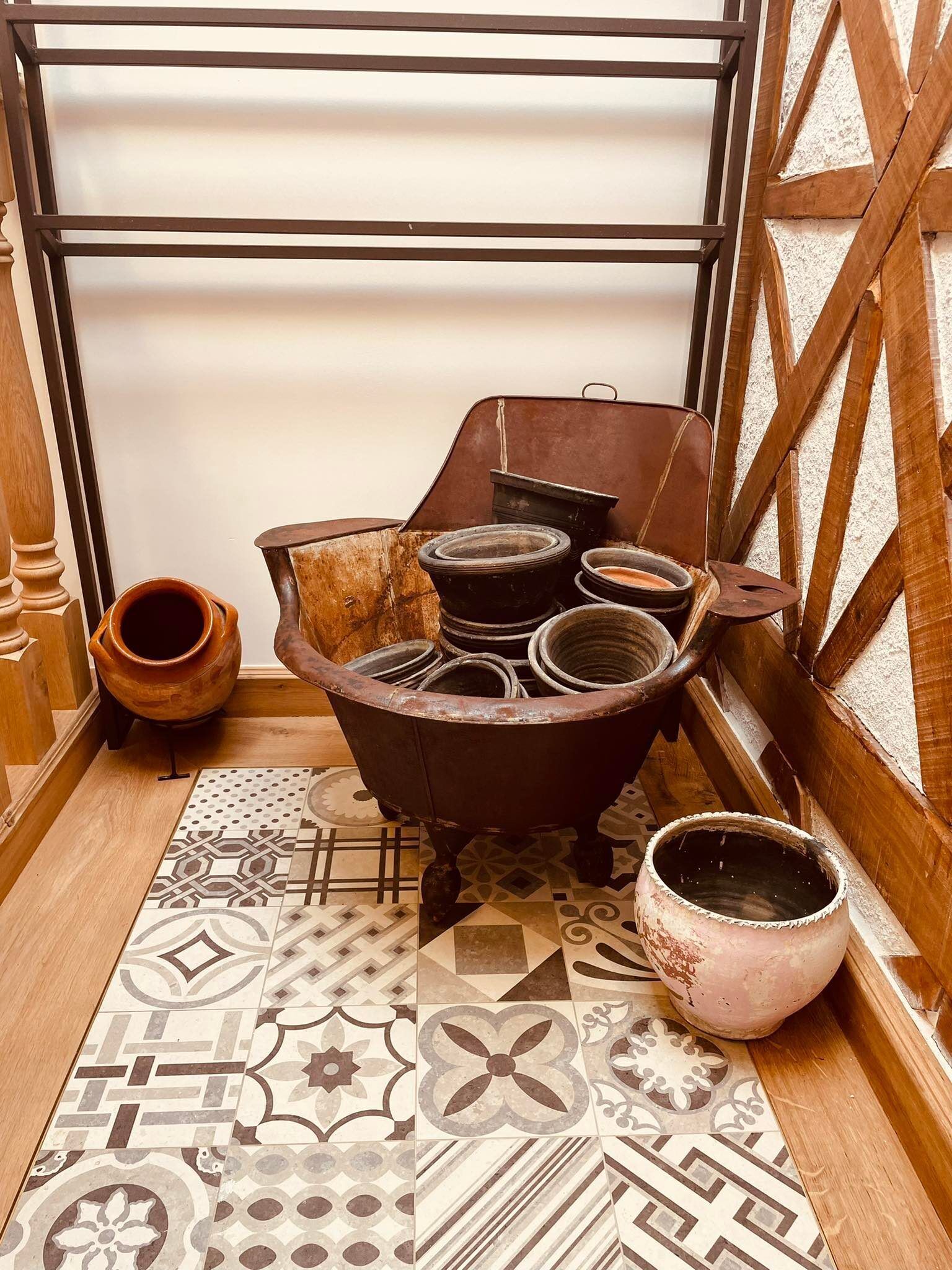 Habitación de esquina con estufa tradicional, varias ollas y un piso con diseño.