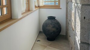 A narrow hallway with a large window and a stone wall. - Casa Guardião (Chaves)