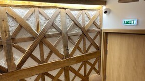 A wooden staircase with a geometric patterned wall and a small wooden table with a spherical object on it. - Casa Guardião (Chaves)
