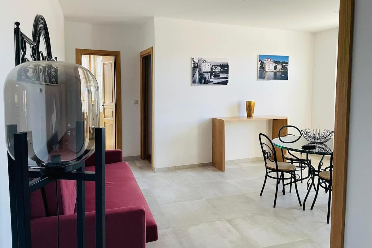 Una sala de estar moderna con un sofá rojo, una mesa de centro de vidrio y un comedor con una mesa pequeña y sillas.