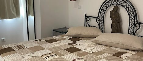 A bedroom with a bed, a nightstand, a wall-mounted lamp, and a statue.