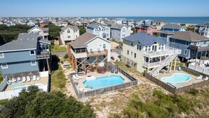 A residential area with multiple houses, a swimming pool, and a view of the ocean.