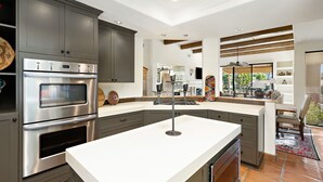 A modern kitchen with built-in appliances, a large island, and a view of the outdoors. - Los Estados #66 - 3 BD /3.5 BA, 2586sf (La Quinta)