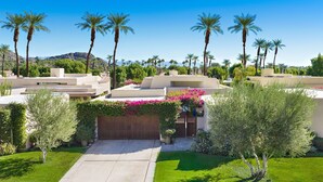 A residential area with palm trees, a well-maintained lawn, and houses with modern architecture. - Los Estados #66 - 3 BD /3.5 BA, 2586sf (La Quinta)