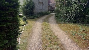 Una casa de piedra con un camino de grava que lleva a un portón de madera.
