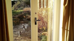 Puerta doble con panel de vidrio que da a un área exterior con camino de piedra y vegetación.