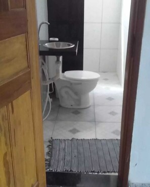 Un baño con inodoro, lavamanos y suelo de baldosas.