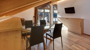 A dining area with a wooden ceiling, a glass table, and black chairs. - Apartment "Baita Emilia e Daniele 13" with Mountain View, Balconies and Wi-Fi (Bormio)