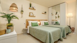 Un dormitorio con dos camas, una mesita de noche, un espejo y una planta en maceta.