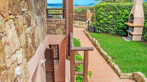 Un muro de piedra, una escalera de madera, un camino pavimentado y un banco de piedra.