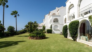 A white building with arched windows and balconies, surrounded by well-maintained lawns and palm trees. - Apartment "240 Front Line Beach La Cala" with Wi-Fi (la cala de mijas)