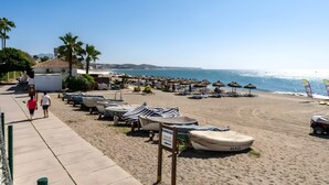 A beach with boats, umbrellas, and a clear sky. - Apartment "240 Front Line Beach La Cala" with Wi-Fi (la cala de mijas)