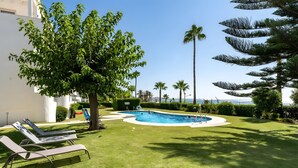A swimming pool surrounded by grass, trees, and lounge chairs. - Apartment "240 Front Line Beach La Cala" with Wi-Fi (la cala de mijas)
