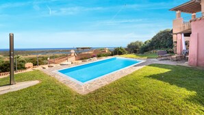 Una piscina con borde de piedra, una pérgola y vistas al mar.