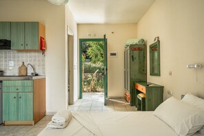 A bedroom with a bed, a small desk, a green wardrobe, and a bathroom with a mirror.