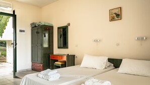 Habitación de hotel con dos camas, un armario de madera, un escritorio y un espejo.