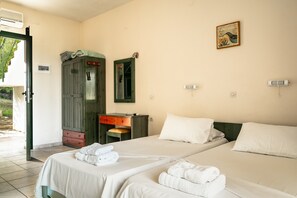 A hotel room with two beds, a wooden wardrobe, a desk, and a mirror.