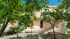 Un patio con una banca, una planta en maceta, una escalera y un edificio con un balcón.