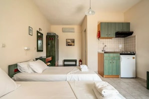 Ein Hotelzimmer mit zwei Betten, einer Küchenzeile, einem Spiegel und einer Klimaanlage.