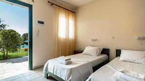 Hotellihuone, jossa on kaksi sänkyä, ikkuna, jossa on verhot, uloskäynnin opaste ja näkymä ulkona olevaan uima-altaaseen.