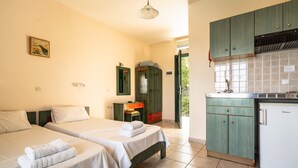 Una stanza con due letti, angolo cottura e una porta che dà sull'esterno.
