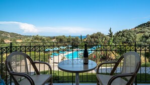 Un balcone con due sedie, un tavolo e una bottiglia di vino. Sullo sfondo, si vede una piscina e la vista del paesaggio circostante.