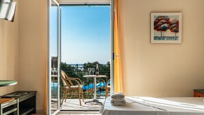 Een hotelkamer met een bed, een tafel met een fles en glazen, een stoel, en een balkon met uitzicht.