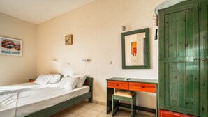Een slaapkamer met een bed, een bureau, een stoel en een kledingkast.