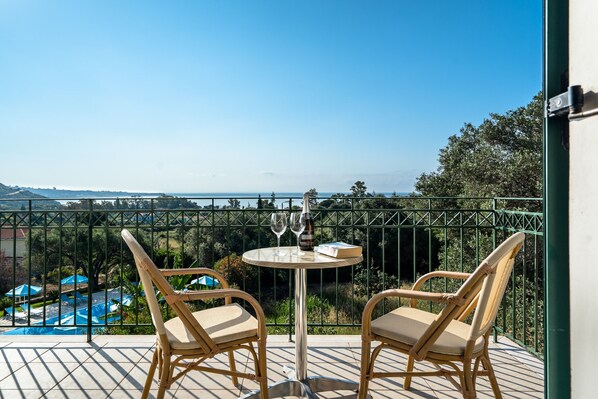 A balcony with two wicker chairs and a table, a bottle, and two wine glasses.