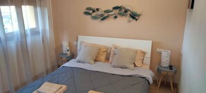 Une chambre à coucher comprenant un lit, deux tables de chevet, un élément de décoration murale et une fenêtre avec des rideaux.