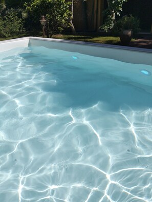 Une piscine aux eaux cristallines, dont on peut distinguer les motifs à la surface, avec un lampadaire en arrière-plan.