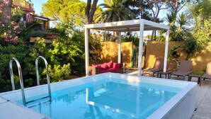 A rectangular swimming pool with metal ladders, a covered seating area with cushions, and a white pergola. - Holiday Home 'Apt in Serra' with Private Pool, Wi-Fi & Air Conditioning (Quartu Sant'Elena)