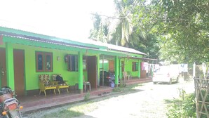A green house with a porch, a motorcycle, and a white van parked outside. - Homocation Ray Homestay (Barnagar)