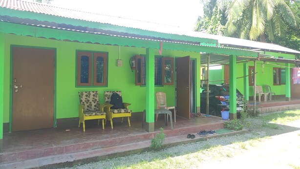 A green house with a porch, a door, and two windows. - Homocation Ray Homestay (Barnagar)
