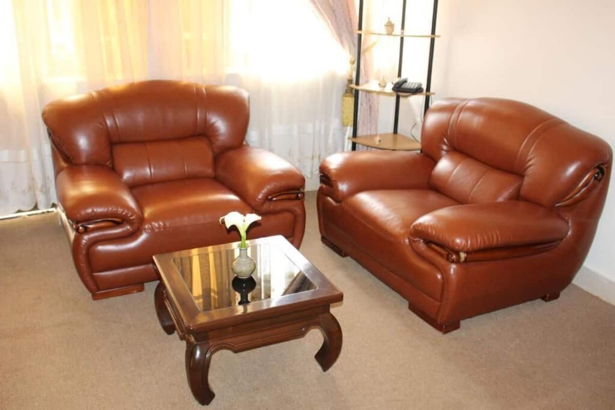 A living room with two brown leather armchairs and a glass coffee table with a vase of flowers.
