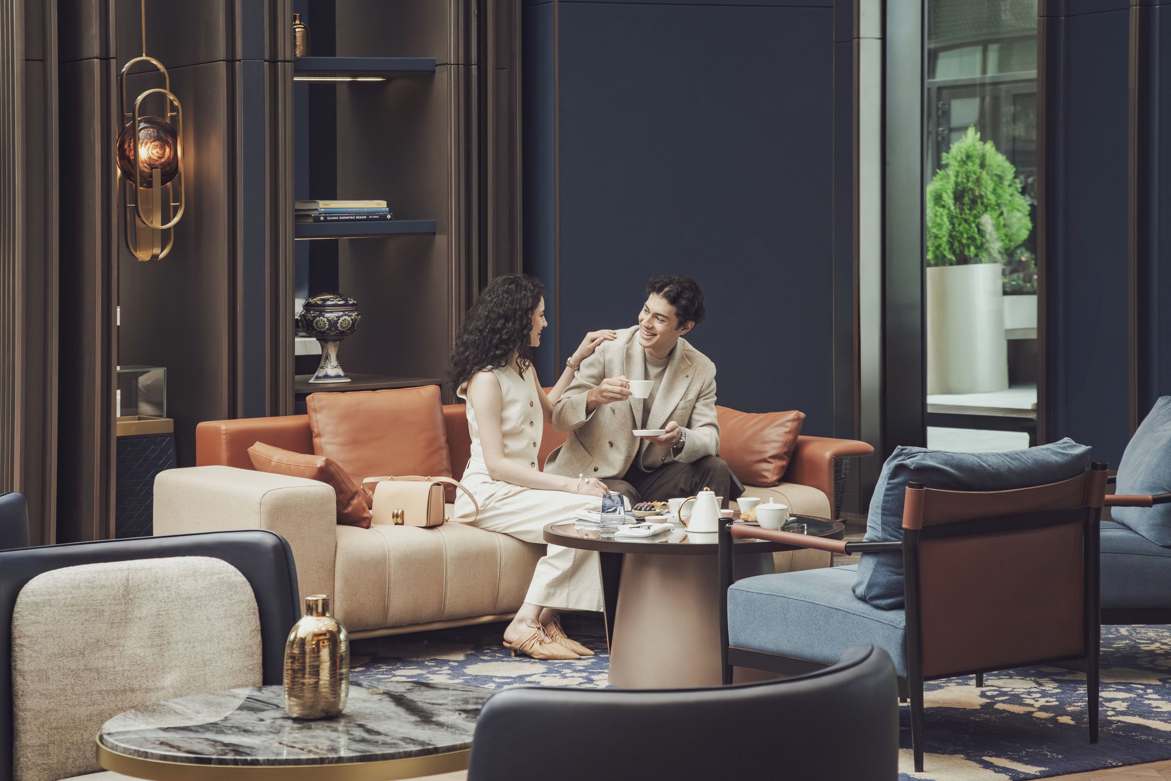 A modern lounge area with leather sofas, a marble coffee table, and a bookshelf with books.