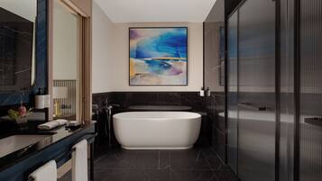 A modern bathroom with a freestanding bathtub, a large mirror, and a contemporary abstract painting.