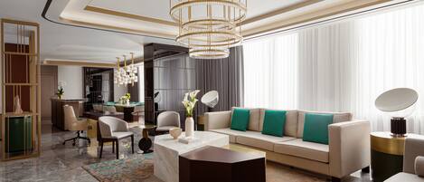 A modern living room with a sofa, coffee table, and chairs. There is a chandelier, a side table, and a large window with curtains.