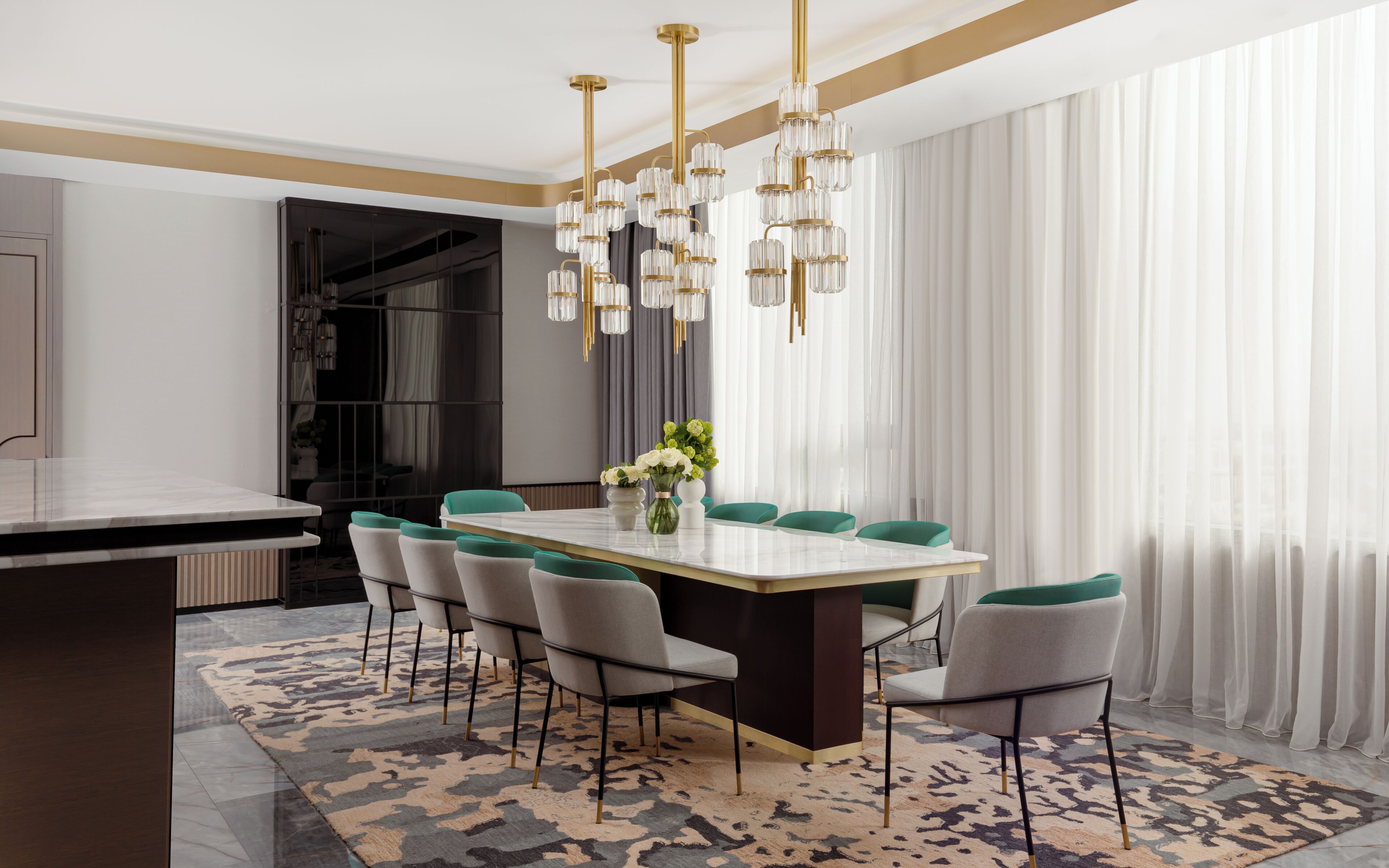A modern dining area with a marble table, green chairs, and a chandelier.