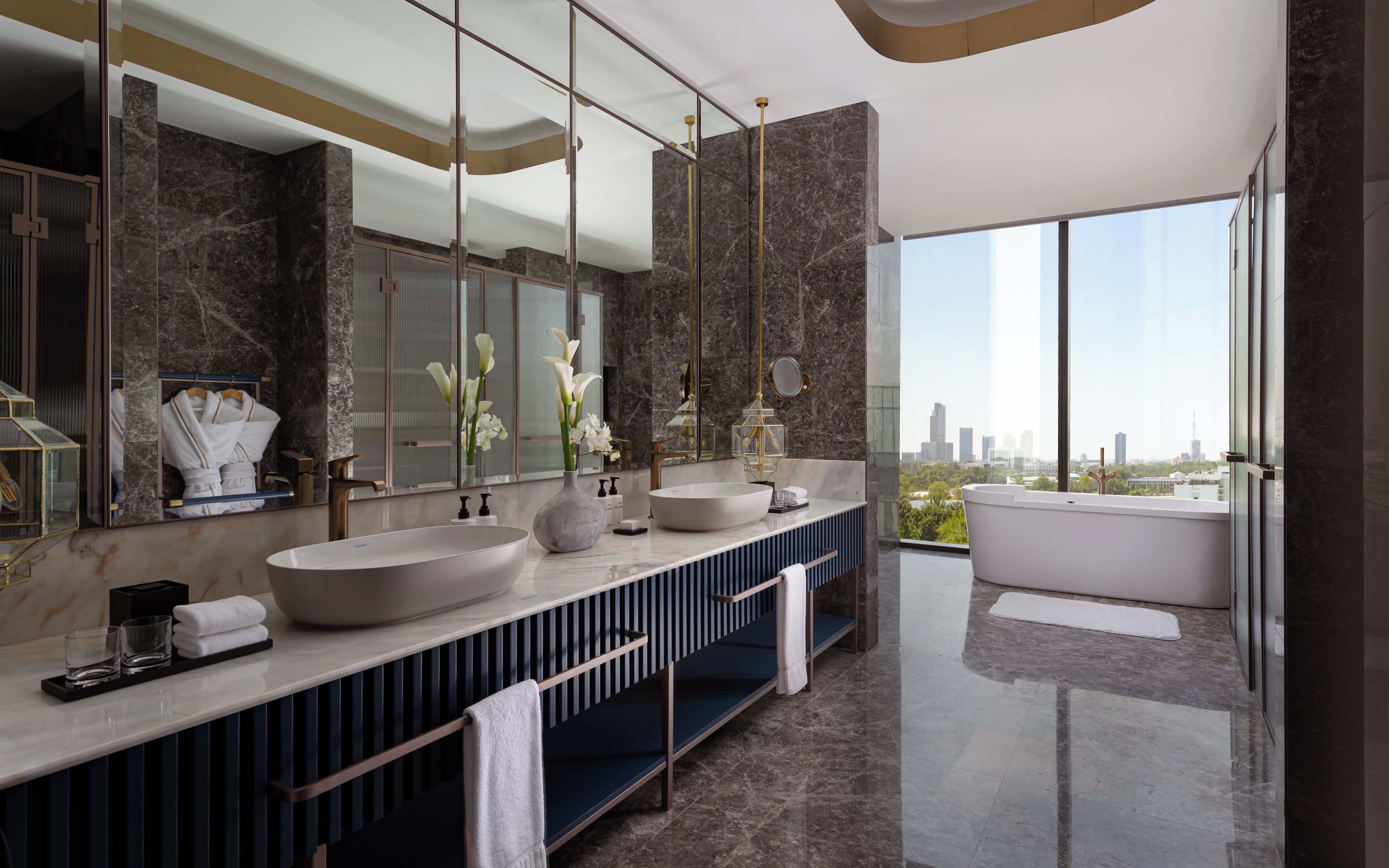 A modern bathroom with two sinks, a large mirror, and a bathtub.