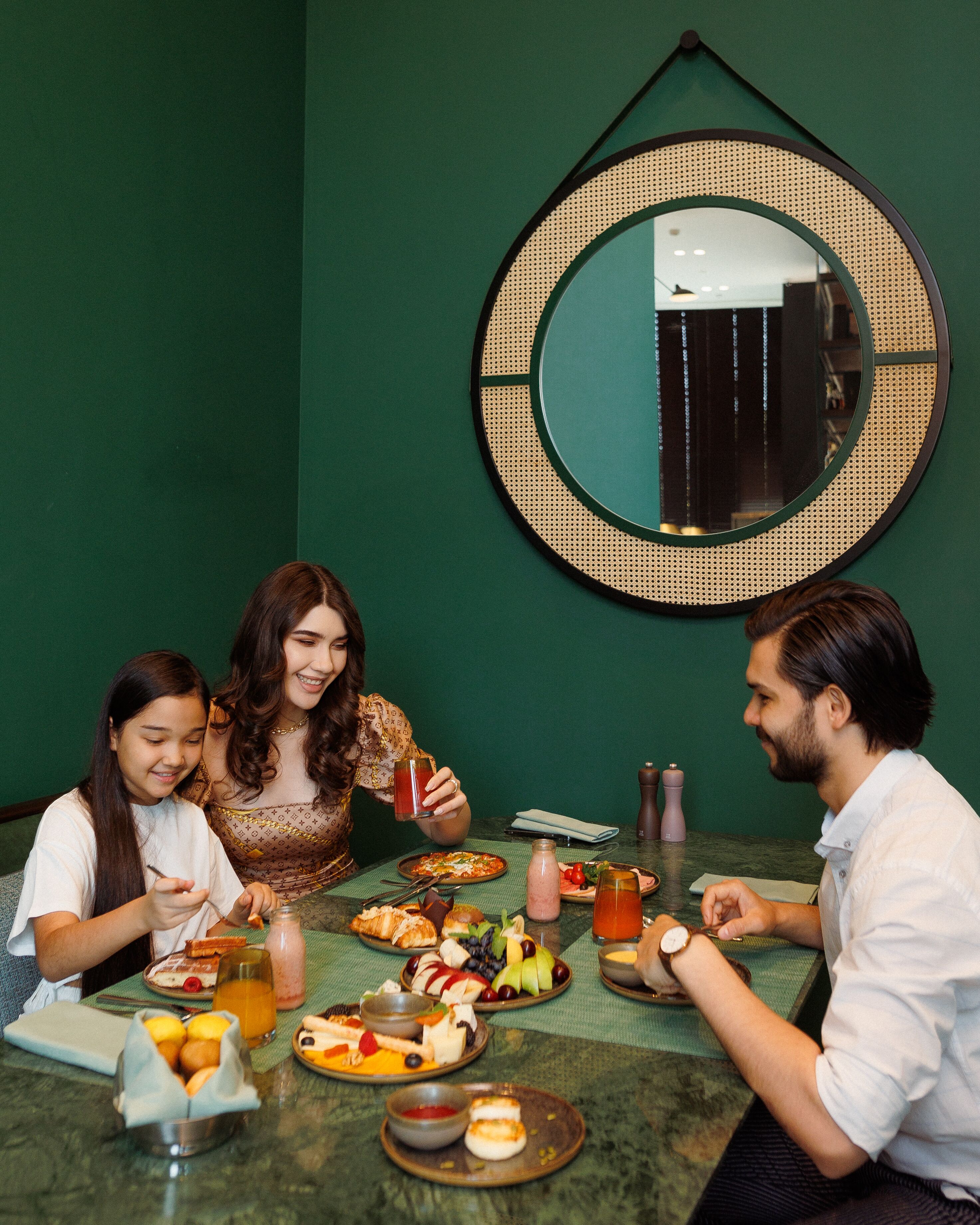 A dining table with various dishes and drinks, a mirror on the wall, and a green wall.