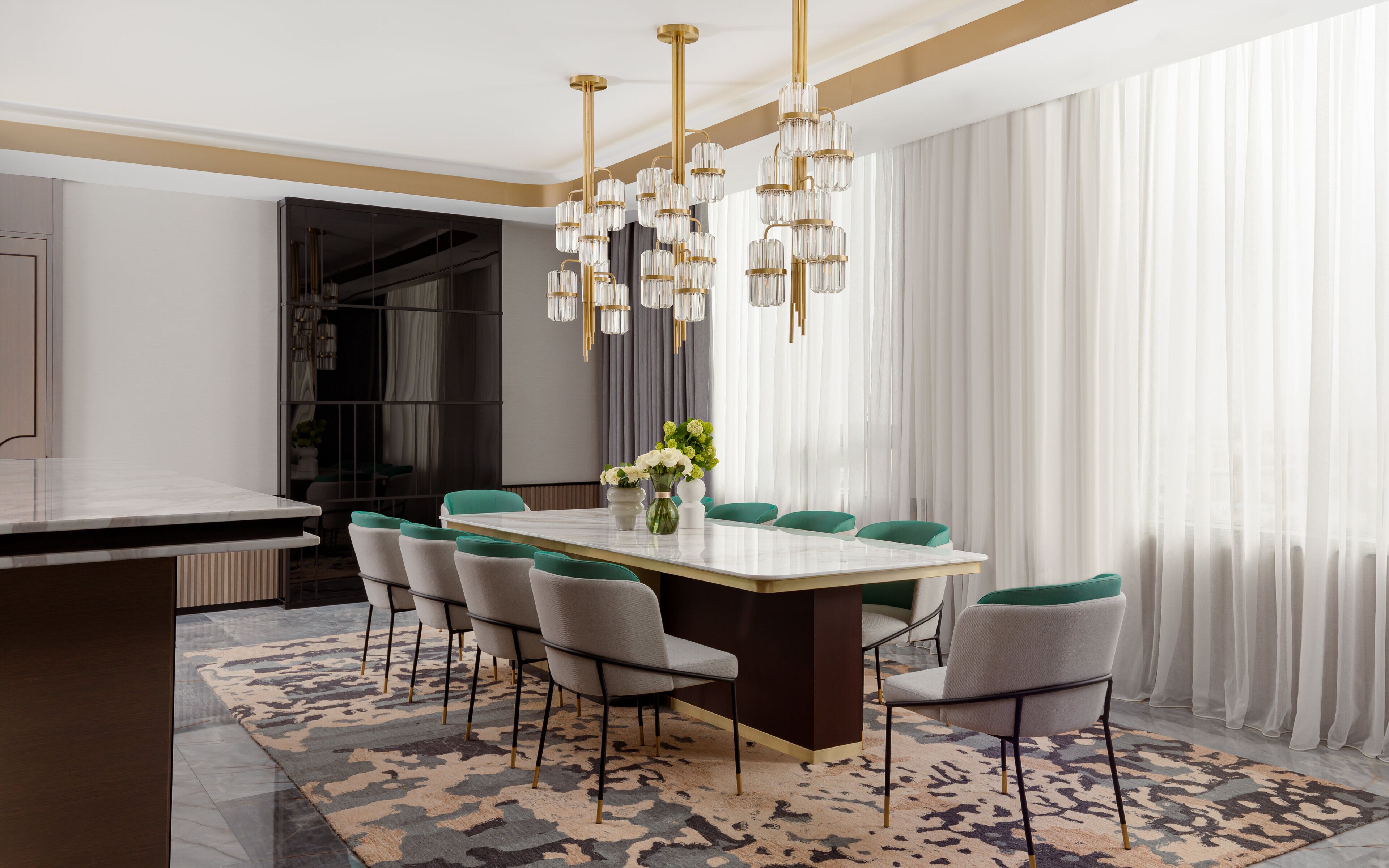 A modern dining area with a marble table, green upholstered chairs, and a patterned rug.