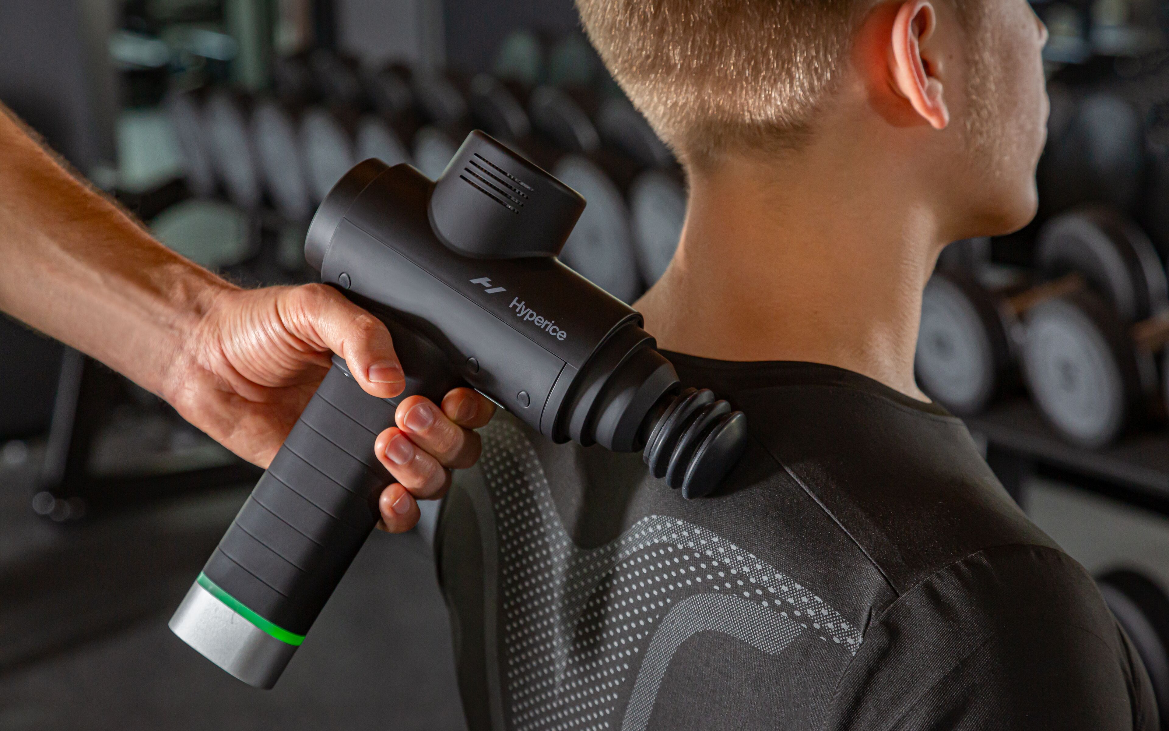 A person using a Hyperice massage gun on another person's back.