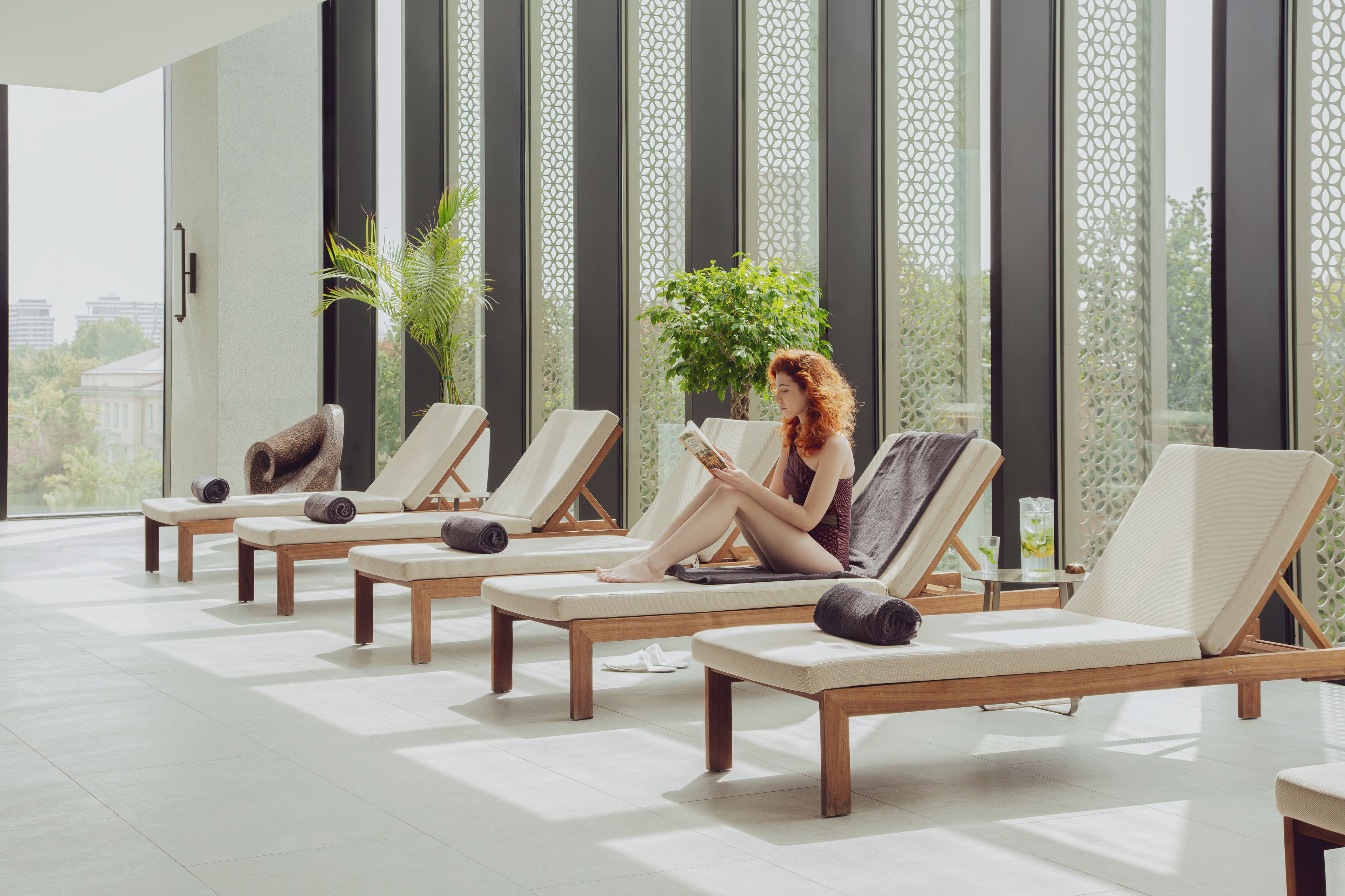 A modern indoor lounge area with multiple sunbeds and potted plants.