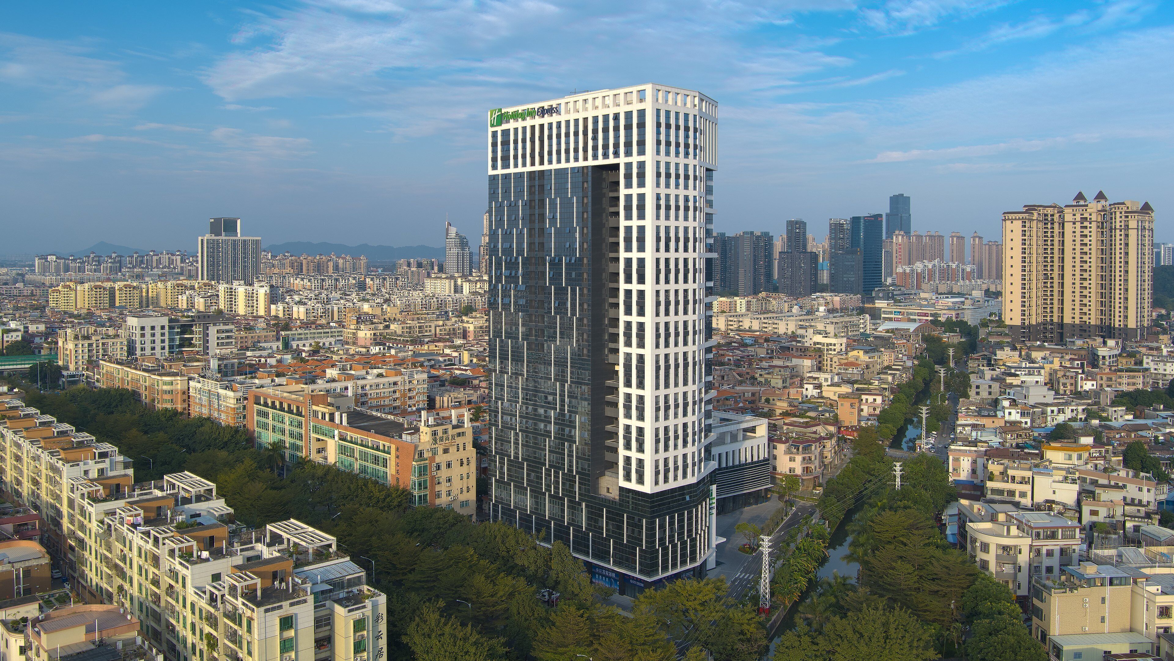 A modern high-rise hotel with a prominent glass facade, surrounded by a dense urban environment.