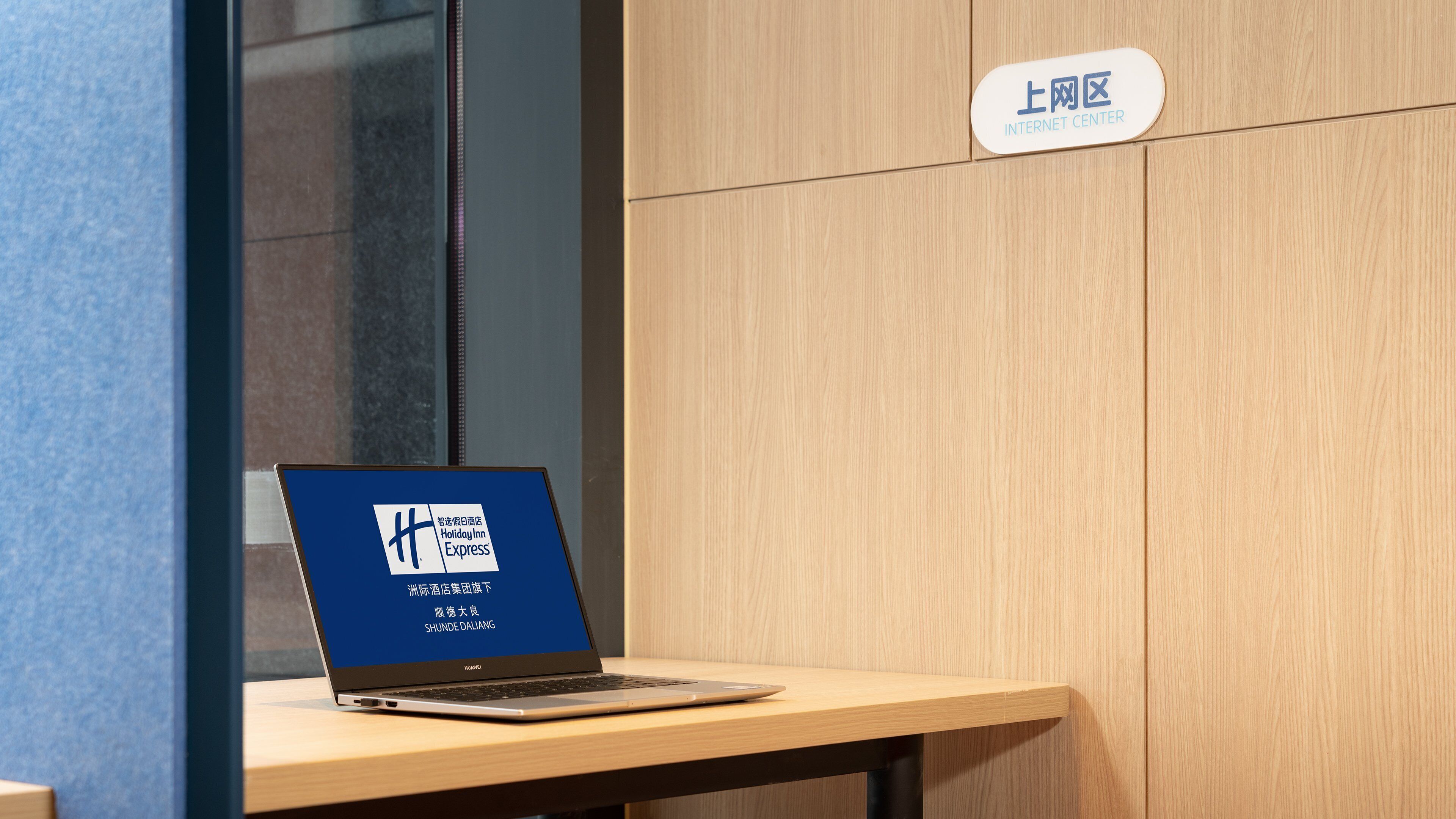A laptop on a wooden table with a sign indicating an internet center.